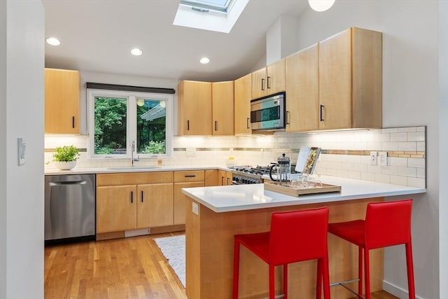 5 Mason St, Lexington, MA 02421 - kitchen featuring appliances with stainless steel finishes, light brown cabinets, a peninsula, a skylight, and recessed lighting
