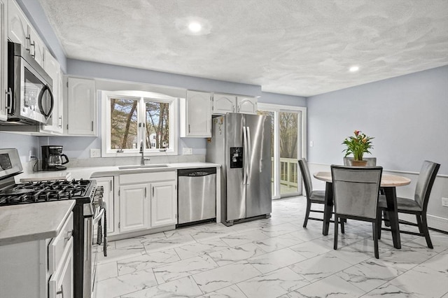 1 Island Rd, Medway, MA 02053 - kitchen with appliances with stainless steel finishes, a sink, light marble finish flooring, light countertops, and white cabinets