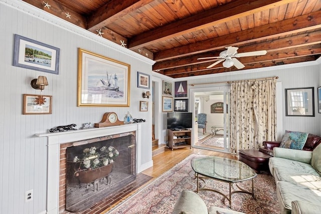 living room featuring ceiling fan, a fireplace, beamed ceiling, light hardwood / wood-style flooring, and wood ceiling