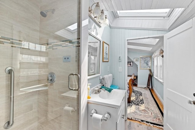 bathroom with walk in shower, vanity, vaulted ceiling with skylight, and wood-type flooring