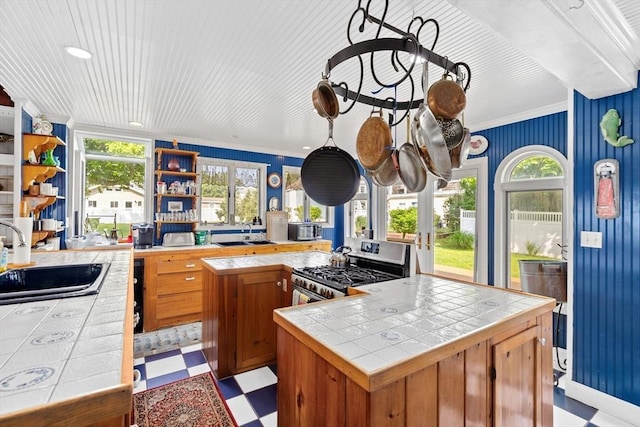 kitchen featuring tile counters, gas stove, french doors, ornamental molding, and sink