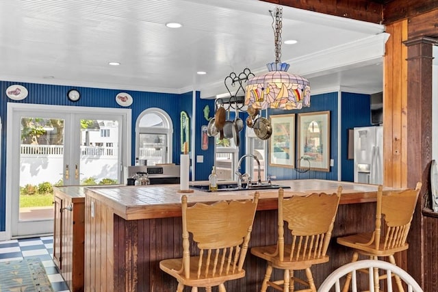 bar with sink, fridge with ice dispenser, crown molding, and french doors