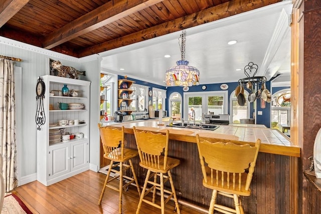 bar featuring light hardwood / wood-style floors, sink, a notable chandelier, tile countertops, and wooden ceiling