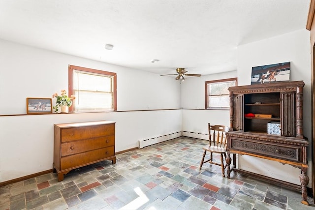 office with a ceiling fan, baseboard heating, stone finish floor, and baseboards