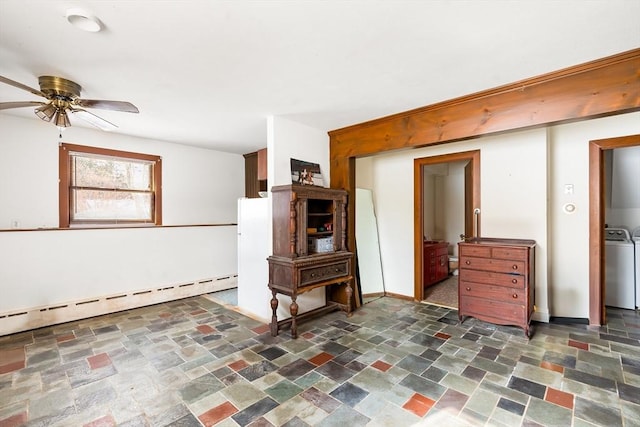 living area with washer / clothes dryer, a baseboard heating unit, stone finish floor, ceiling fan, and baseboards