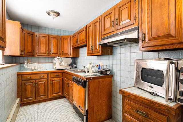 kitchen featuring under cabinet range hood, tile counters, brown cabinets, and dishwasher