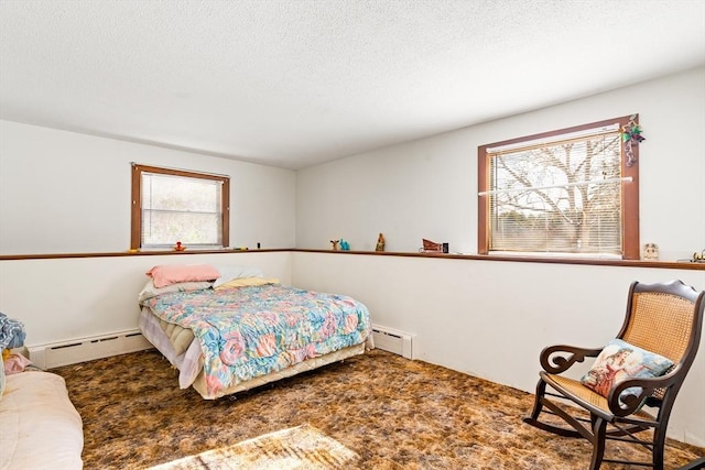 bedroom featuring a baseboard heating unit, carpet flooring, and a textured ceiling