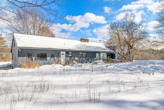 snow covered house featuring a chimney