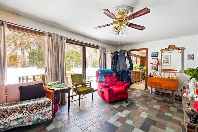 sitting room featuring stone finish floor and ceiling fan