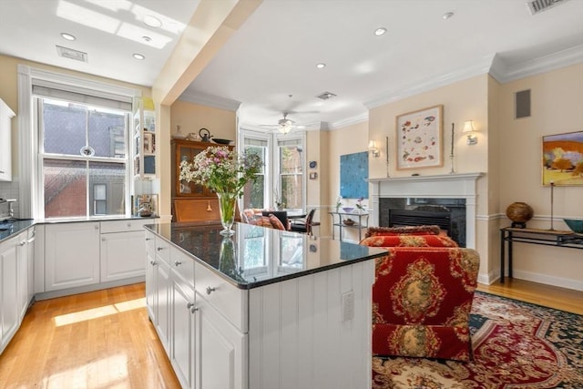 151 Beacon St Unit 4, Boston, MA 02116 - kitchen with ornamental molding, light wood-style floors, a kitchen island, a fireplace, and white cabinets