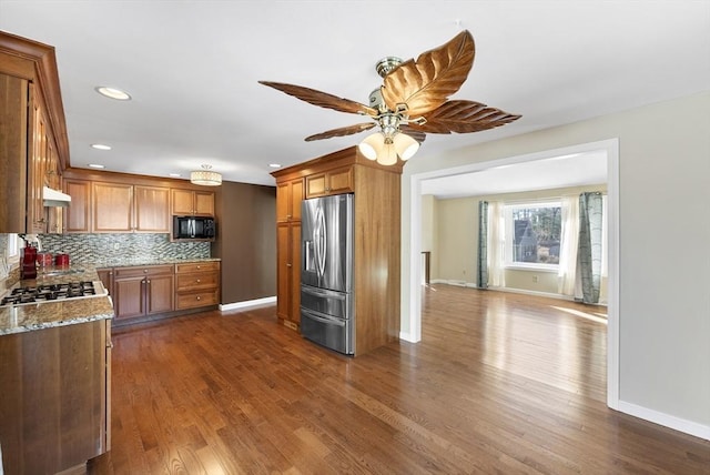 kitchen featuring dark wood-type flooring, stainless steel refrigerator with ice dispenser, ceiling fan, tasteful backsplash, and light stone counters