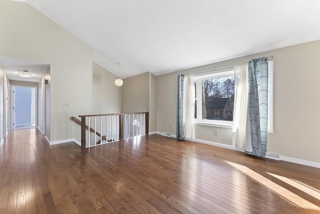 spare room featuring high vaulted ceiling and dark wood-type flooring