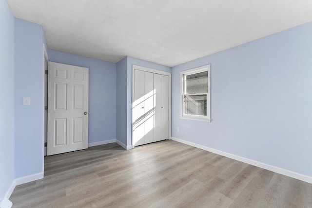 unfurnished bedroom with light wood-type flooring and a closet