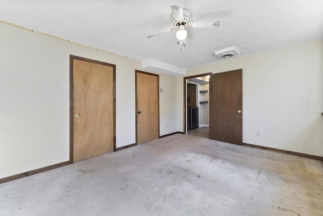 unfurnished bedroom with multiple closets, ceiling fan, and light colored carpet