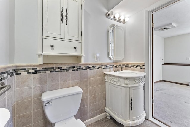 bathroom with vanity, toilet, and tile walls