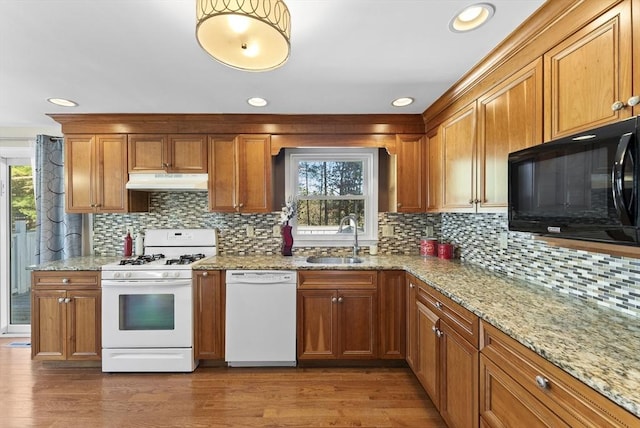 kitchen with decorative backsplash, white appliances, hardwood / wood-style flooring, and sink