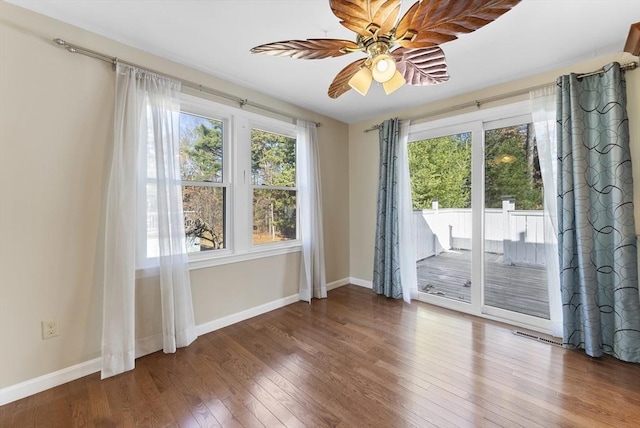 spare room with dark hardwood / wood-style floors, ceiling fan, and a healthy amount of sunlight