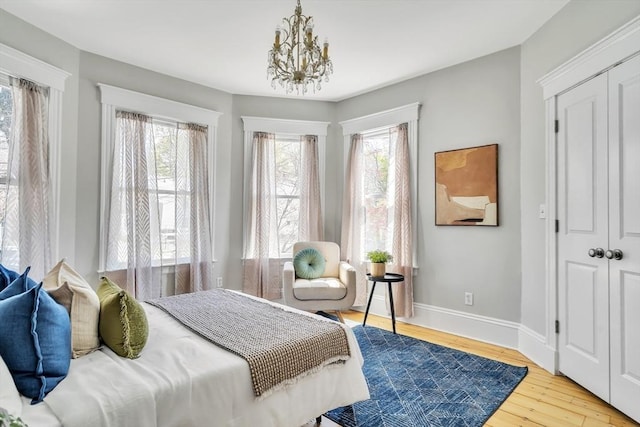 bedroom with baseboards, wood finished floors, and a notable chandelier