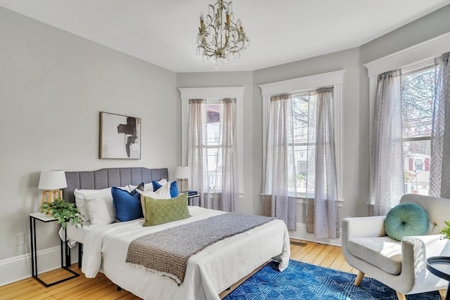 bedroom featuring a notable chandelier, multiple windows, and wood finished floors
