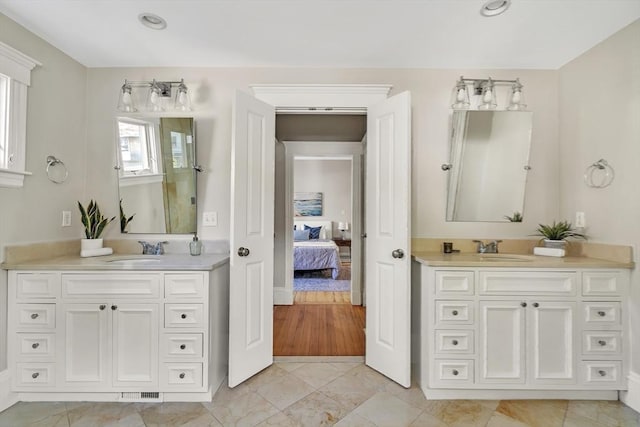 bathroom featuring connected bathroom, two vanities, and a sink