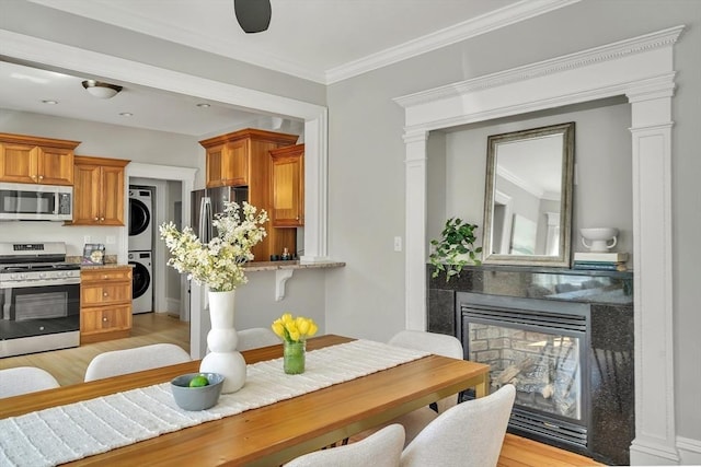 interior space with stacked washer / dryer, light wood-style floors, brown cabinets, a multi sided fireplace, and appliances with stainless steel finishes