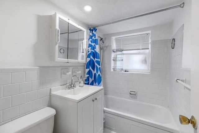 full bathroom with toilet, tile walls, vanity, and shower / tub combo with curtain