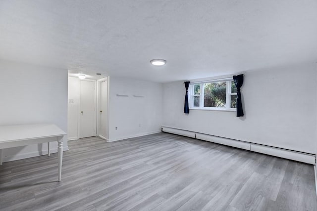 empty room with light wood-type flooring and baseboard heating