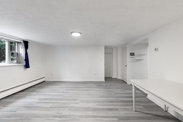 unfurnished room featuring baseboard heating and light hardwood / wood-style floors