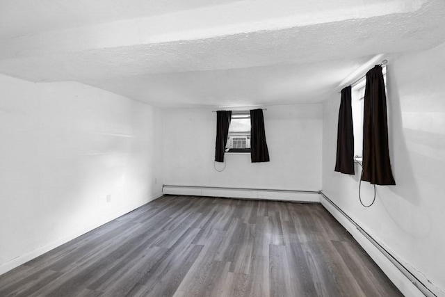 spare room featuring a textured ceiling, a baseboard heating unit, and dark hardwood / wood-style flooring