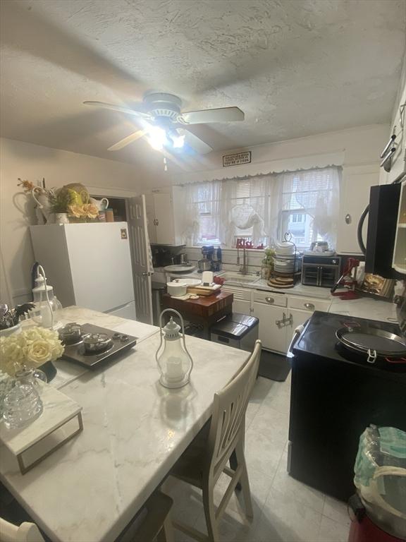 kitchen featuring light stone countertops, sink, white refrigerator, a textured ceiling, and white cabinets