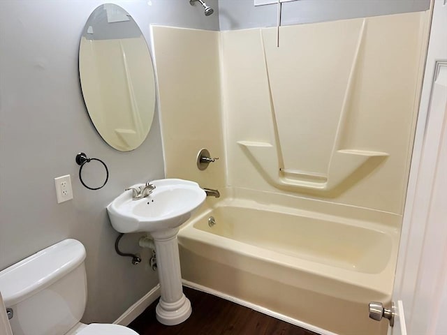 bathroom featuring hardwood / wood-style flooring, toilet, and washtub / shower combination