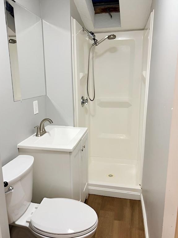 bathroom featuring hardwood / wood-style flooring, toilet, a shower, and vanity