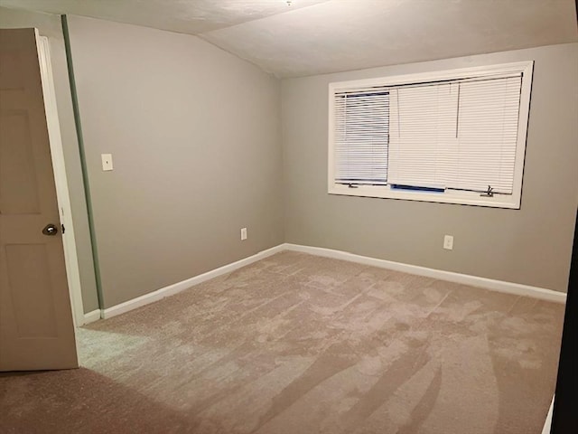 carpeted spare room featuring vaulted ceiling