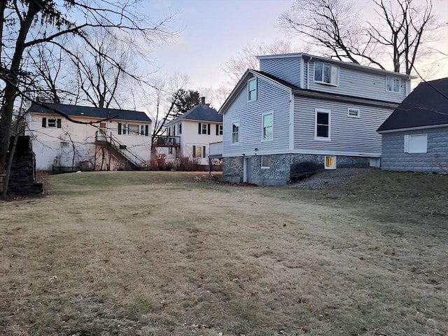 back house at dusk featuring a lawn