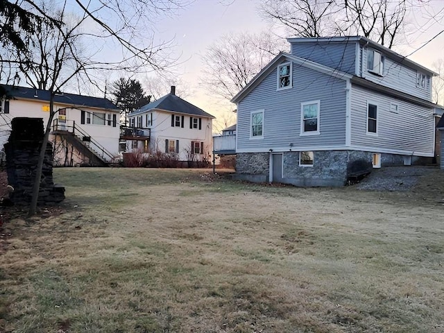 back house at dusk featuring a lawn