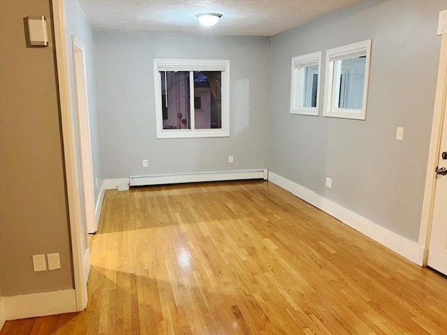 unfurnished room featuring a baseboard radiator, a textured ceiling, and light wood-type flooring