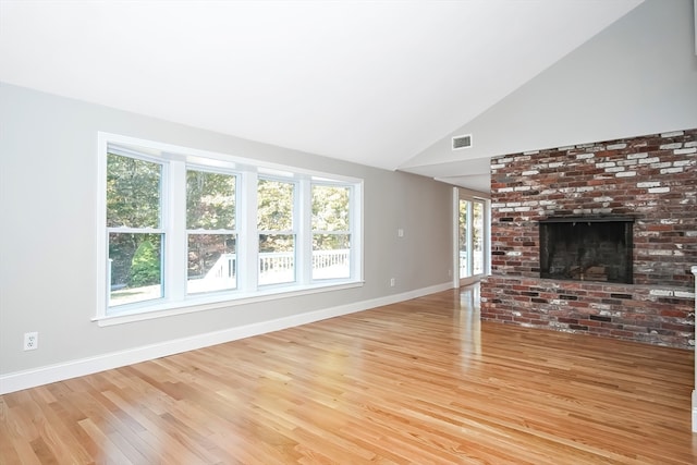 unfurnished living room featuring a brick fireplace, high vaulted ceiling, and light hardwood / wood-style flooring