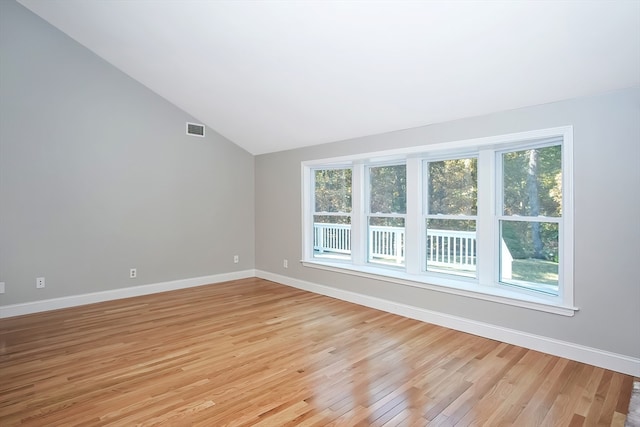 unfurnished room with lofted ceiling and light wood-type flooring