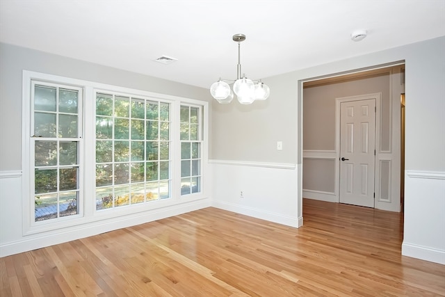 unfurnished dining area with a chandelier and light hardwood / wood-style flooring