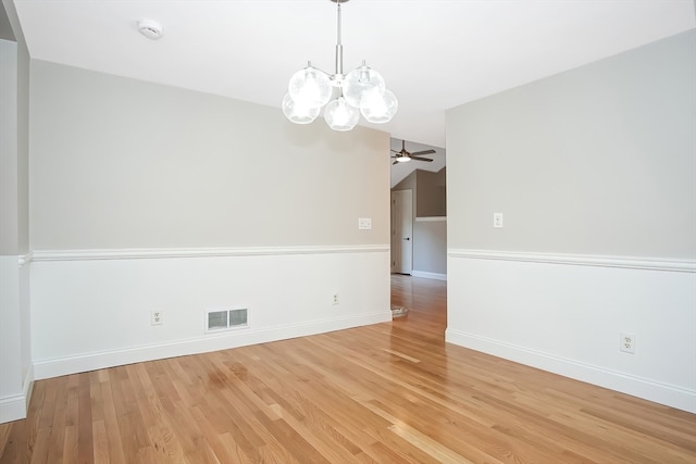 spare room with ceiling fan with notable chandelier and light wood-type flooring