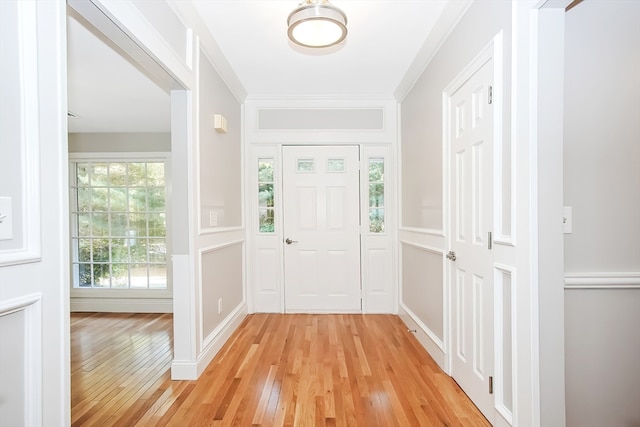 foyer entrance with crown molding and light wood-type flooring