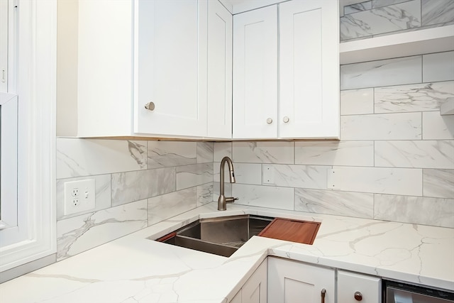 kitchen featuring light stone counters, sink, and white cabinets