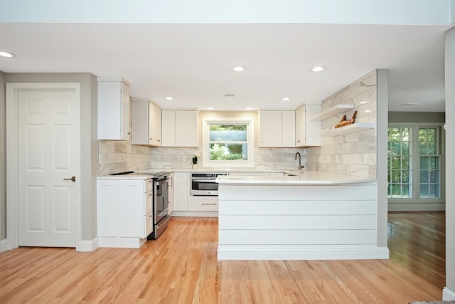 kitchen featuring tasteful backsplash, stainless steel appliances, sink, light hardwood / wood-style floors, and white cabinetry