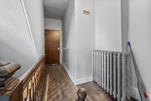 hall with dark wood-type flooring and radiator heating unit