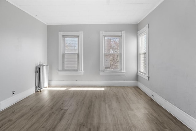 spare room featuring hardwood / wood-style floors, radiator heating unit, and ornamental molding