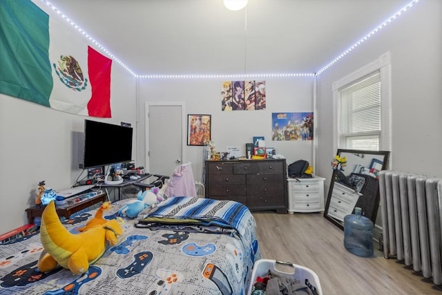 bedroom with radiator heating unit and light hardwood / wood-style floors