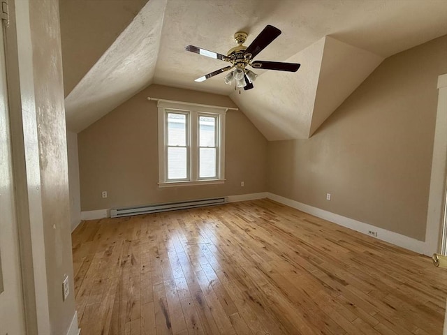 additional living space featuring light wood finished floors, a textured ceiling, lofted ceiling, and a baseboard radiator