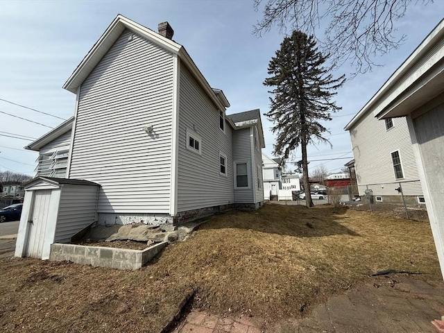 view of property exterior featuring a storage shed and a chimney