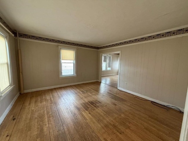 spare room featuring ornamental molding, baseboards, and hardwood / wood-style floors