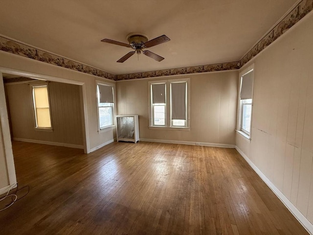 unfurnished room with hardwood / wood-style flooring, a ceiling fan, baseboards, and a healthy amount of sunlight